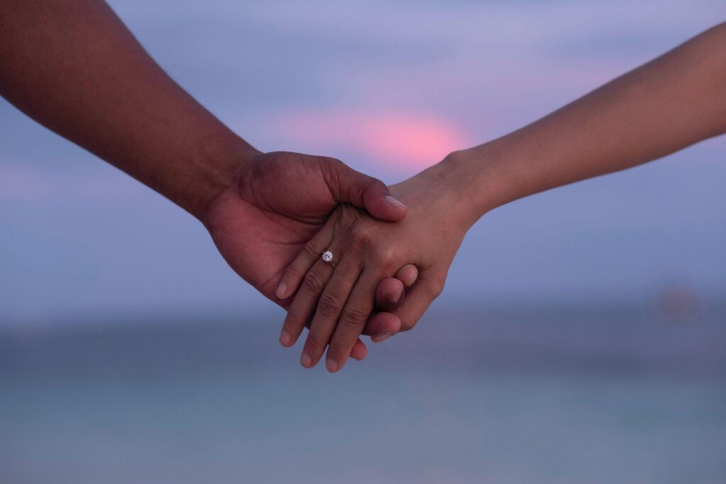 A photo of a couple holding hands, only the hands are visible in the frame